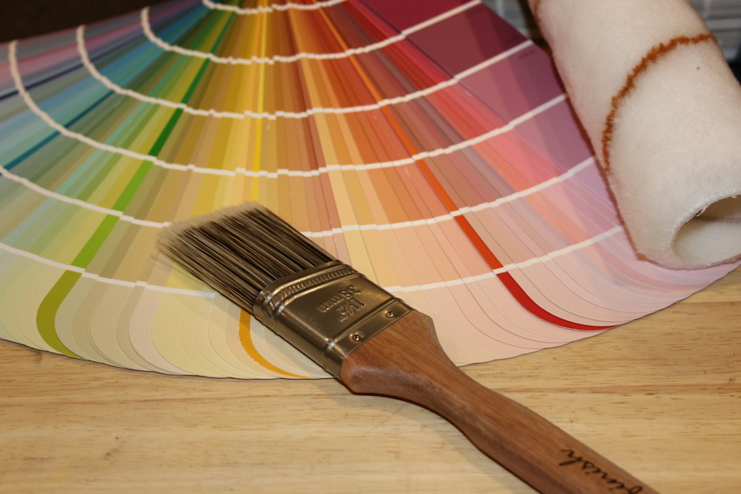 Paint color fan with a paintbrush and roller on a wooden surface